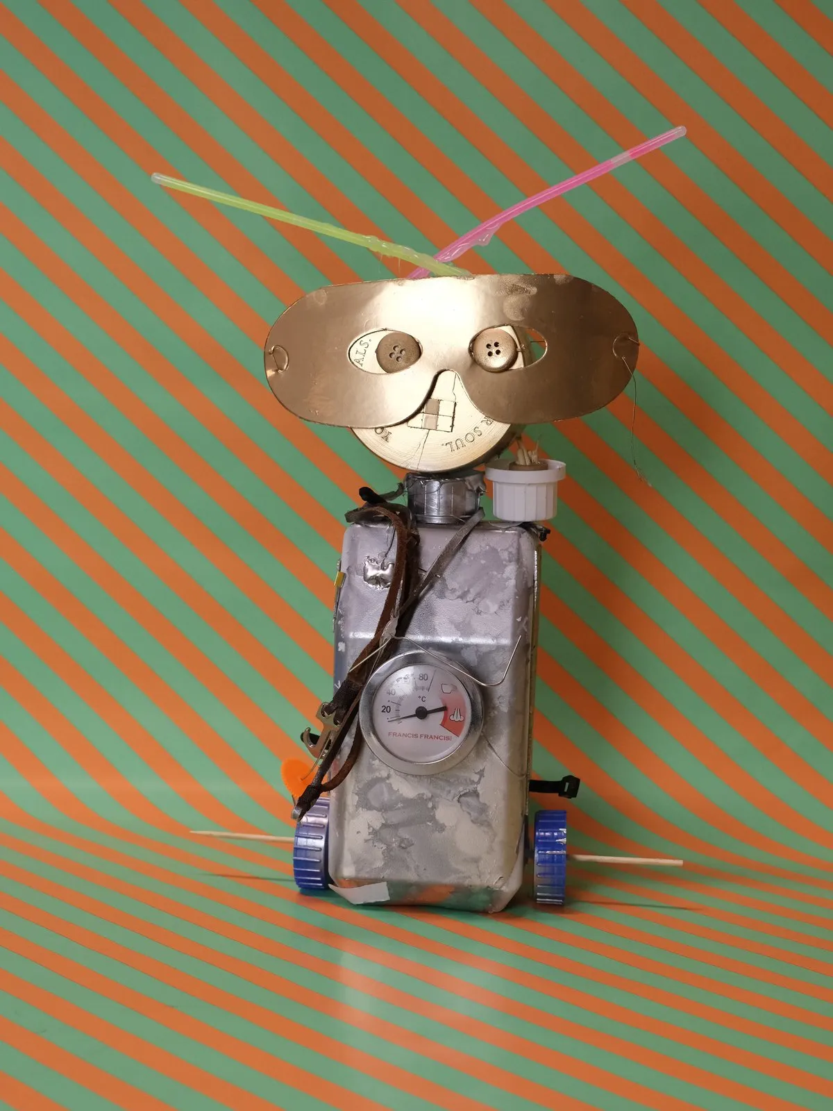 Een zilveren robot met een lachend gezicht, tegen oranje strepen
